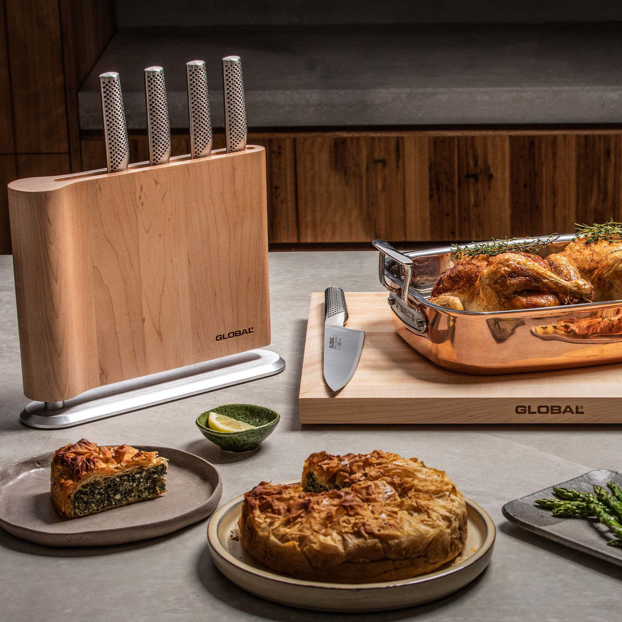Kitchen scene with a wooden knife block,Global branded, on a kitchen counter with food and cutlery.